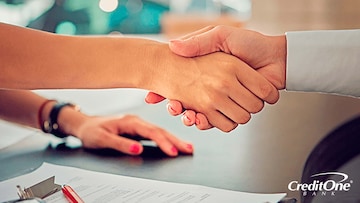 Two people shaking hands as they close a deal on a new car purchase